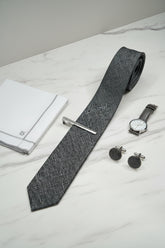 Navy textured silk tie displayed with matching cufflinks and pocket square.